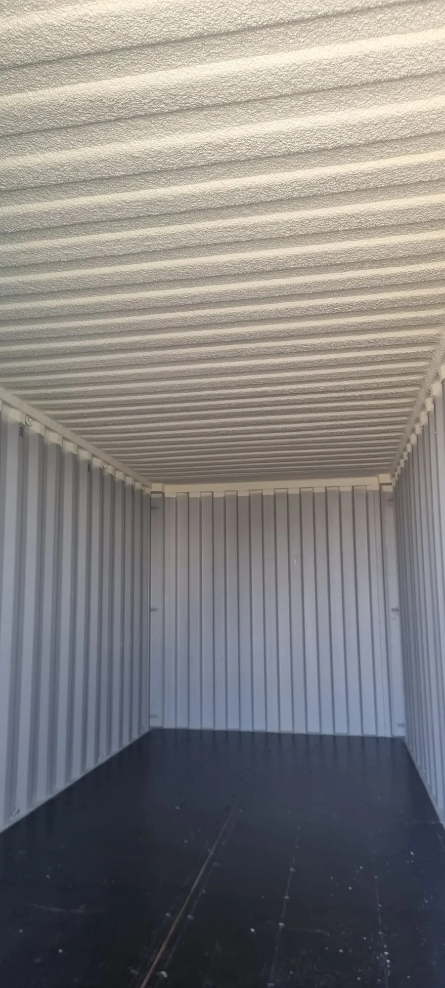 A ceiling coating on the corrugated steel inside a storage container.